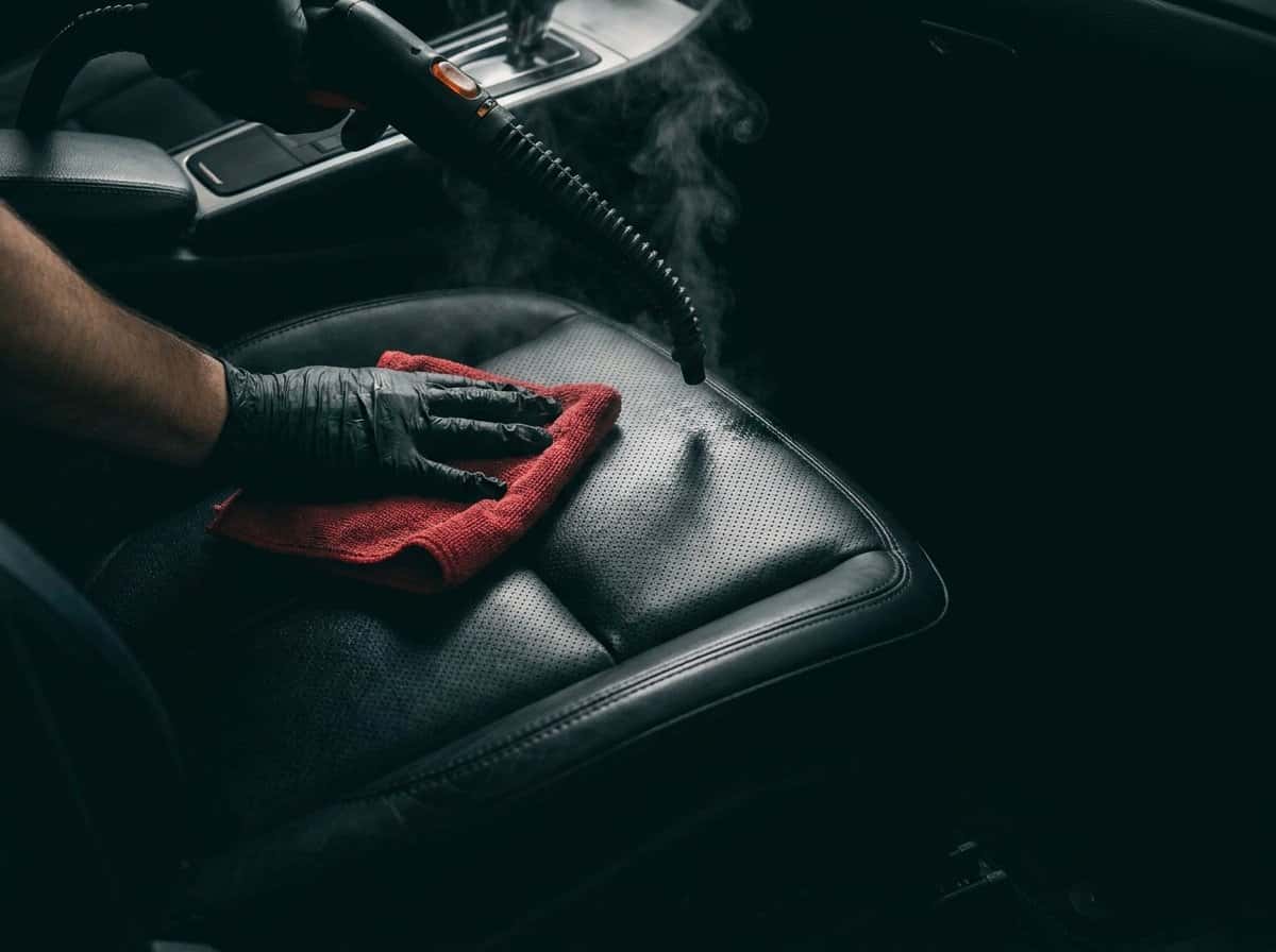 Steam cleaning black leather seats with a red microfiber towel